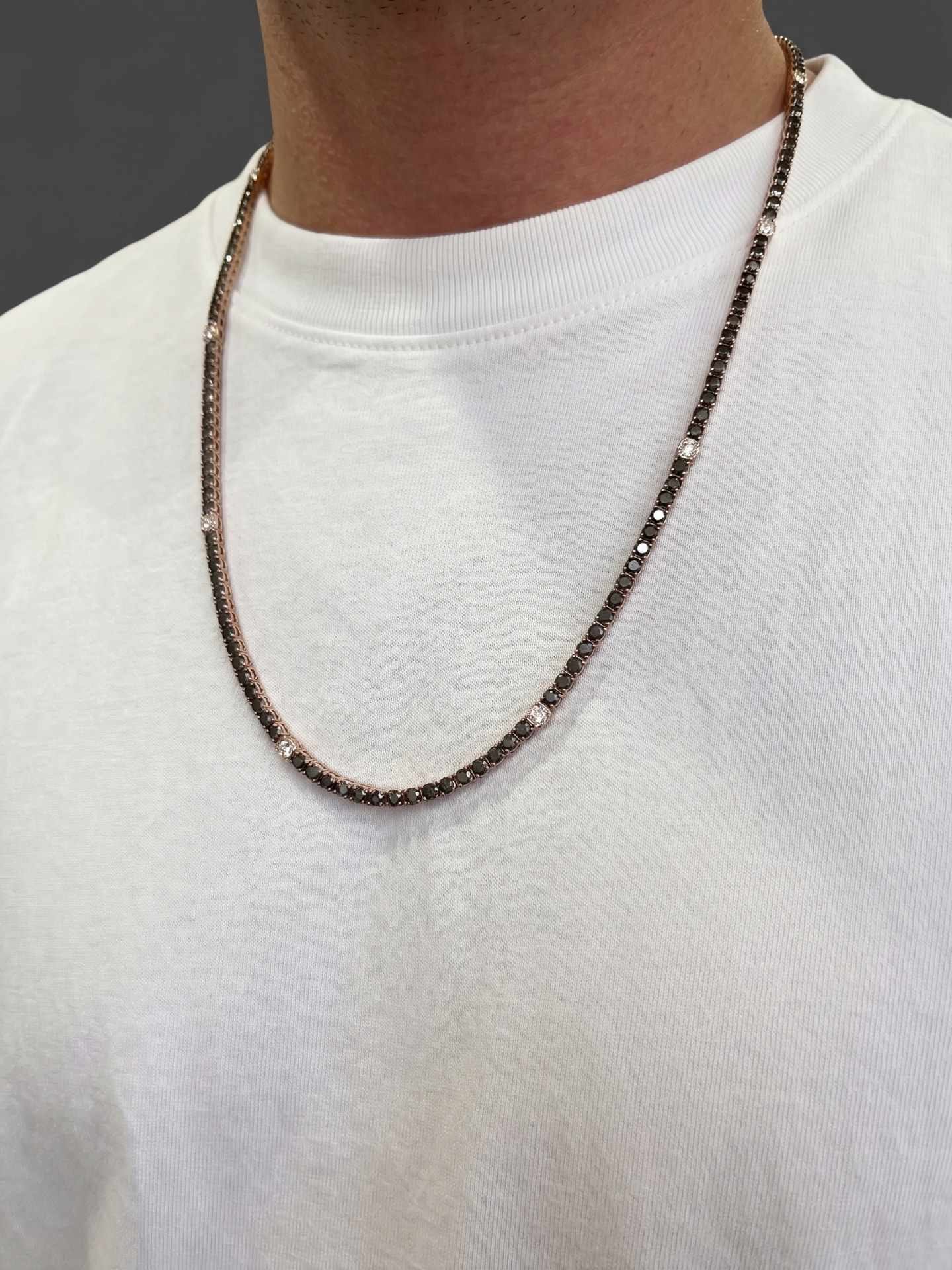 Rose gold chain necklace with black and white stones on a white shirt