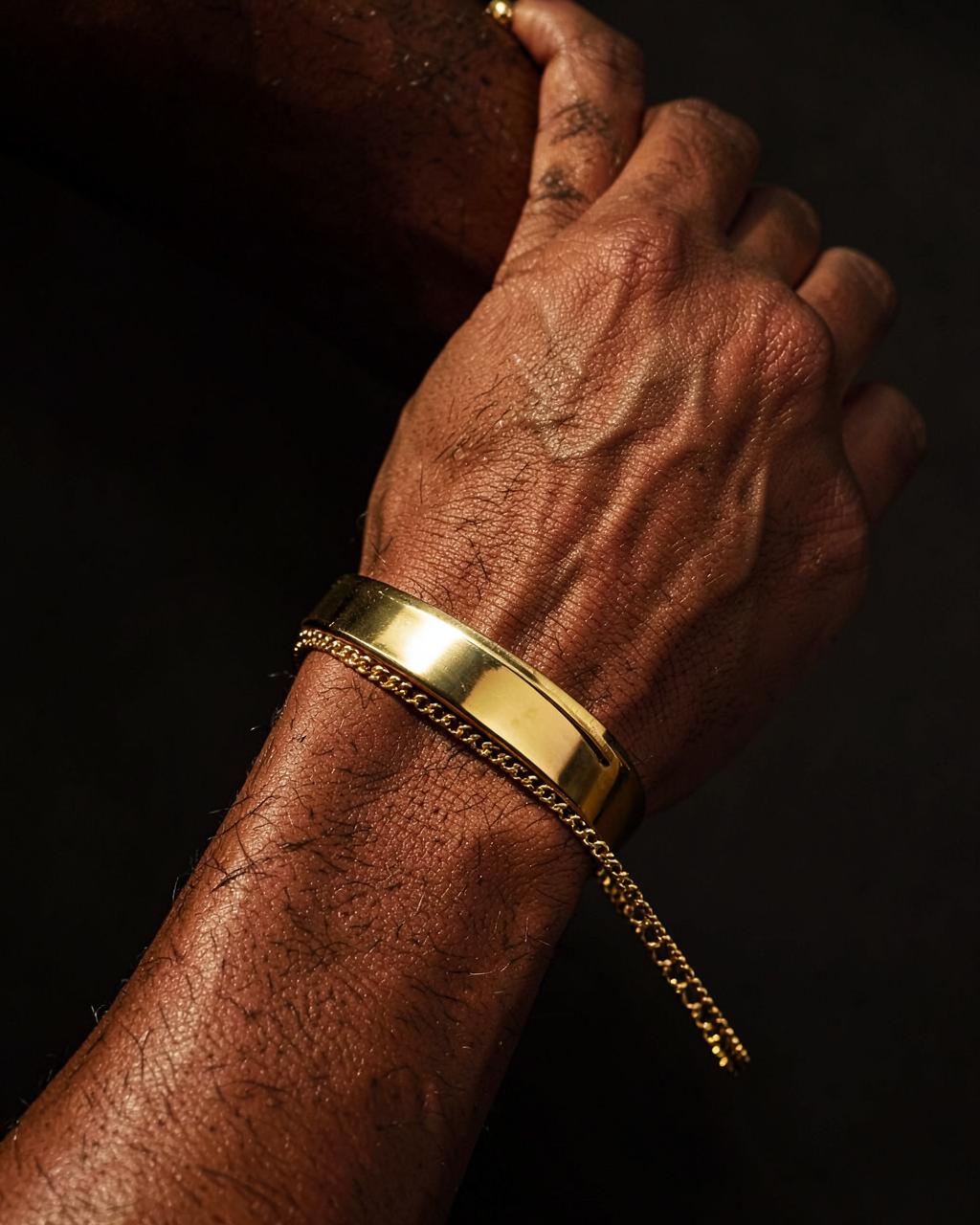 Solid gold cuff and chain bracelet on a man's wrist